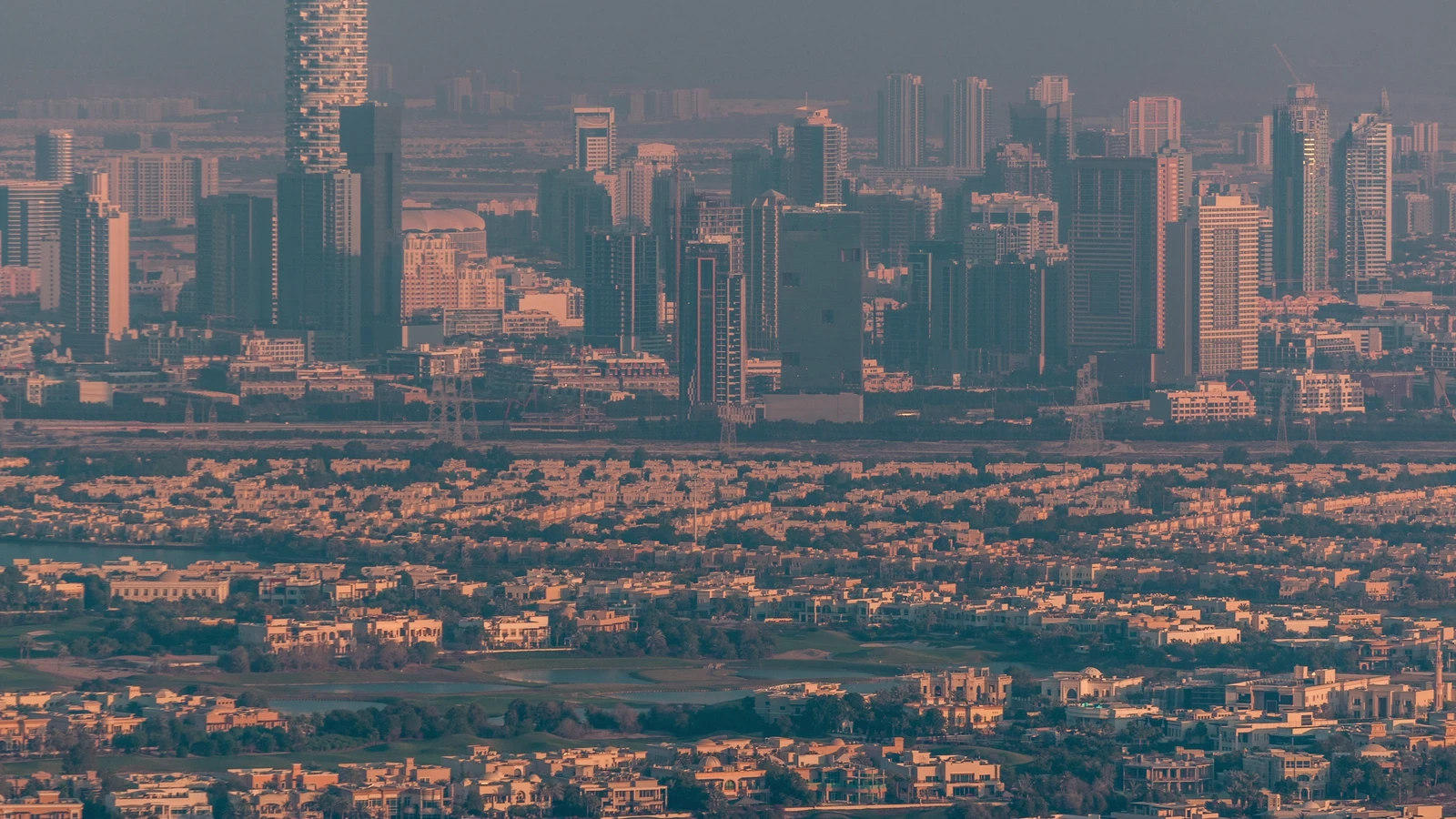 Elevated view of villas and high-rise residential towers in warm evening light
